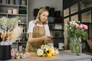 Caucasian woman taking photo of finished flowers bouquet for social media. Floristry concept.
