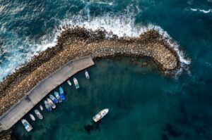 Drone aerial fishing harbour with boats stormy waves, blue sea